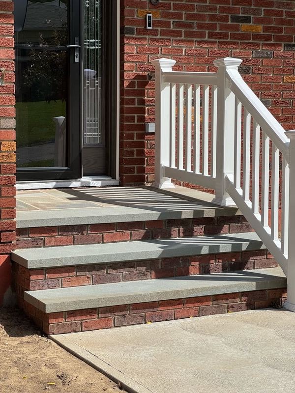 Brick stoop with bluestone treads and white vinyl step railing
