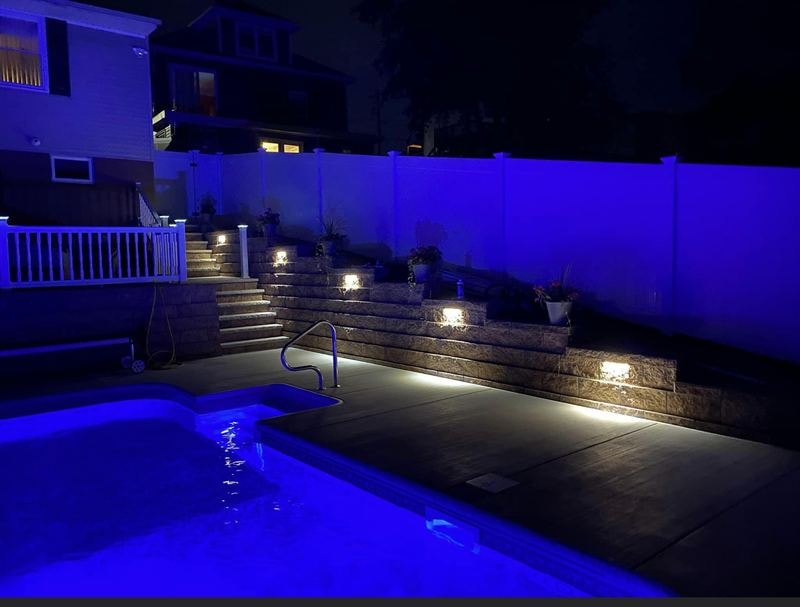 Pool area at night with white vinyl fence and railing